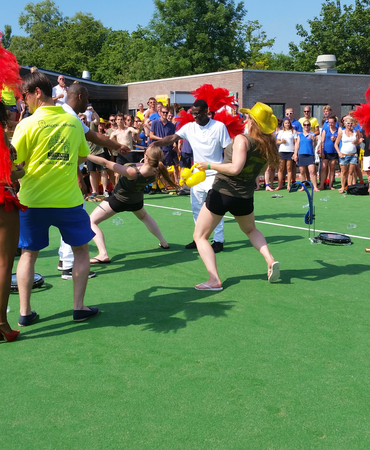 Gasten doen mee aan limbo tijdens een buitenfeest